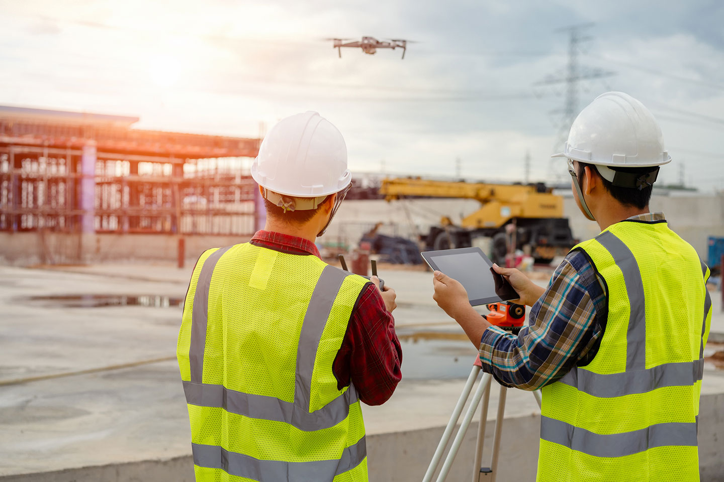 Two operators with yellow safety jackets operating a drone.