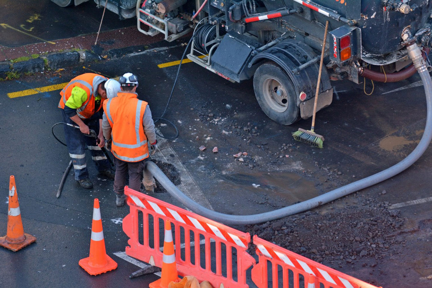 Sewerage operators cleaning street.